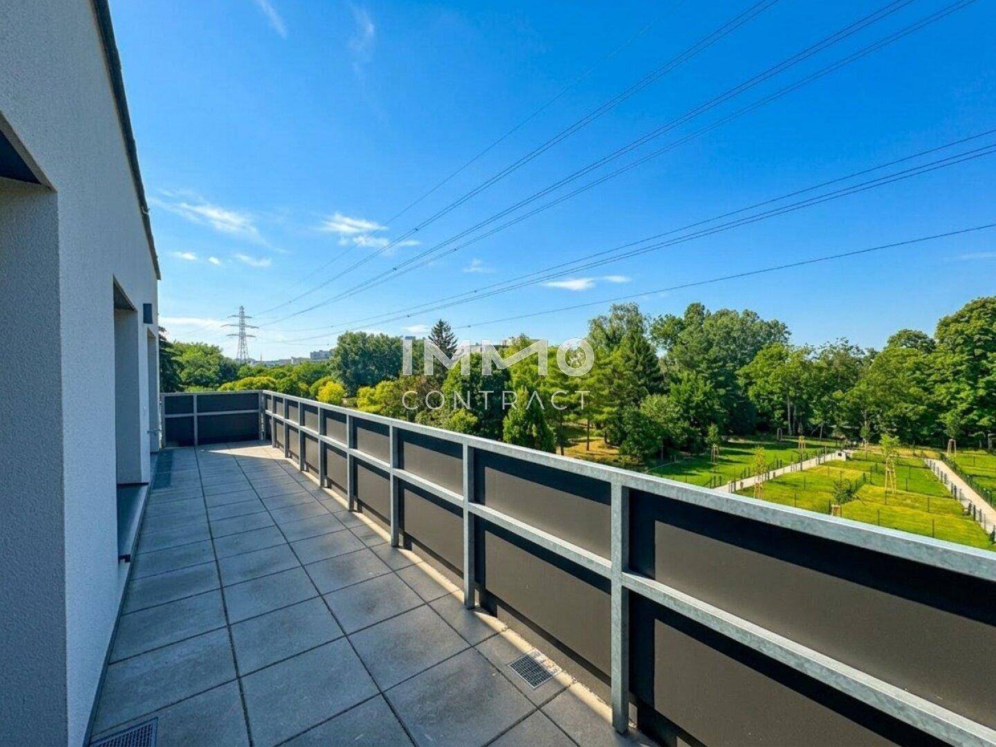 Weitläufige, geflieste Terrasse mit Blick auf die grüne Umgebung unter strahlend blauem Himmel.