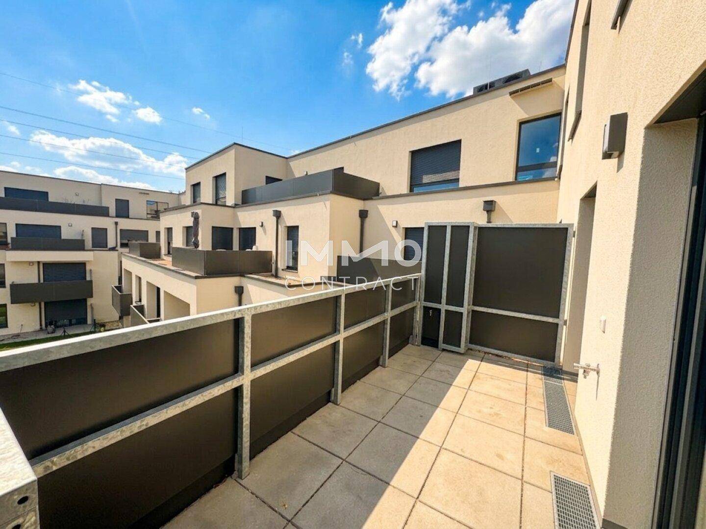 Geräumiger, unmöblierter Balkon mit Betonboden und Blick auf die umliegenden Gebäude.