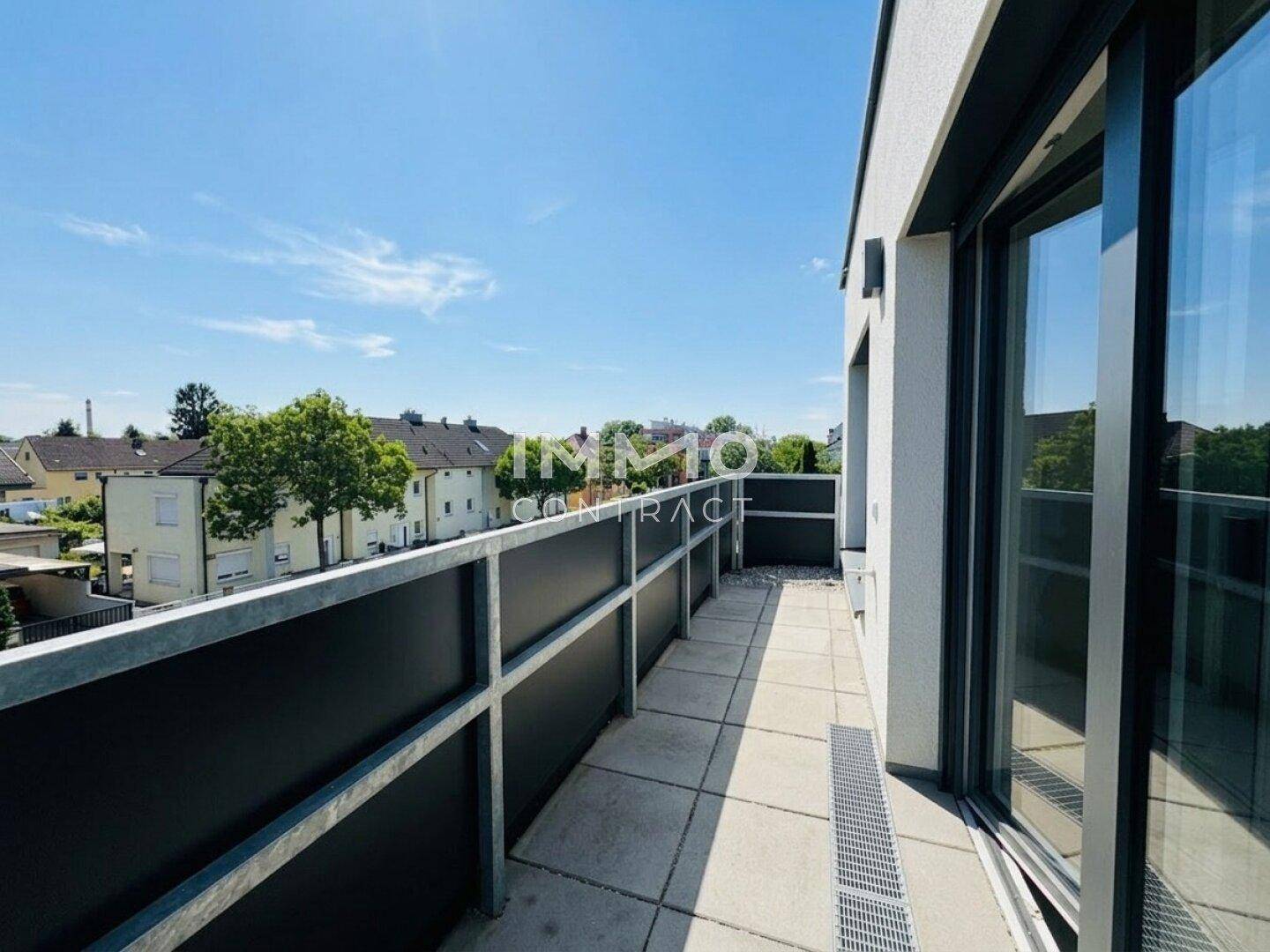 Langer Balkon mit moderner Brüstung und Blick auf die umliegende Wohngegend.