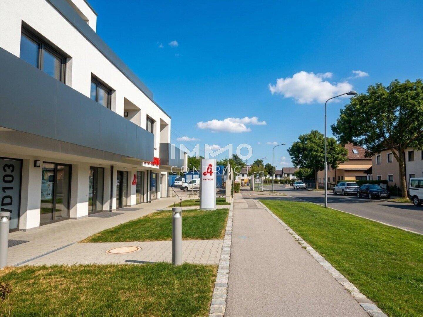 Moderne Gebäudefassade entlang einer Straße mit Geschäften im Erdgeschoss und Wohnungen darüber.
