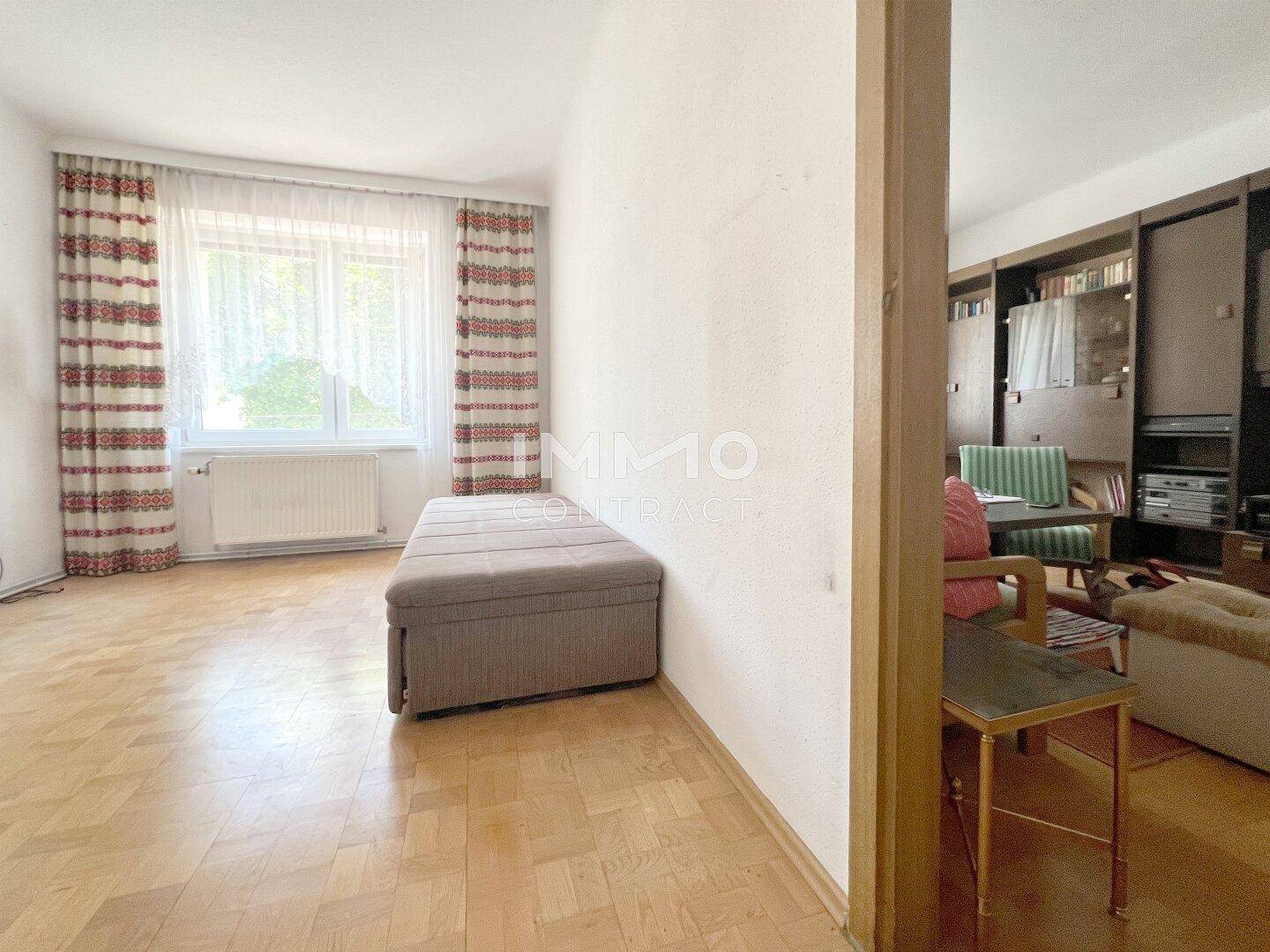 Helles Zimmer mit Parkettboden und großem Fenster, vielseitig nutzbar.