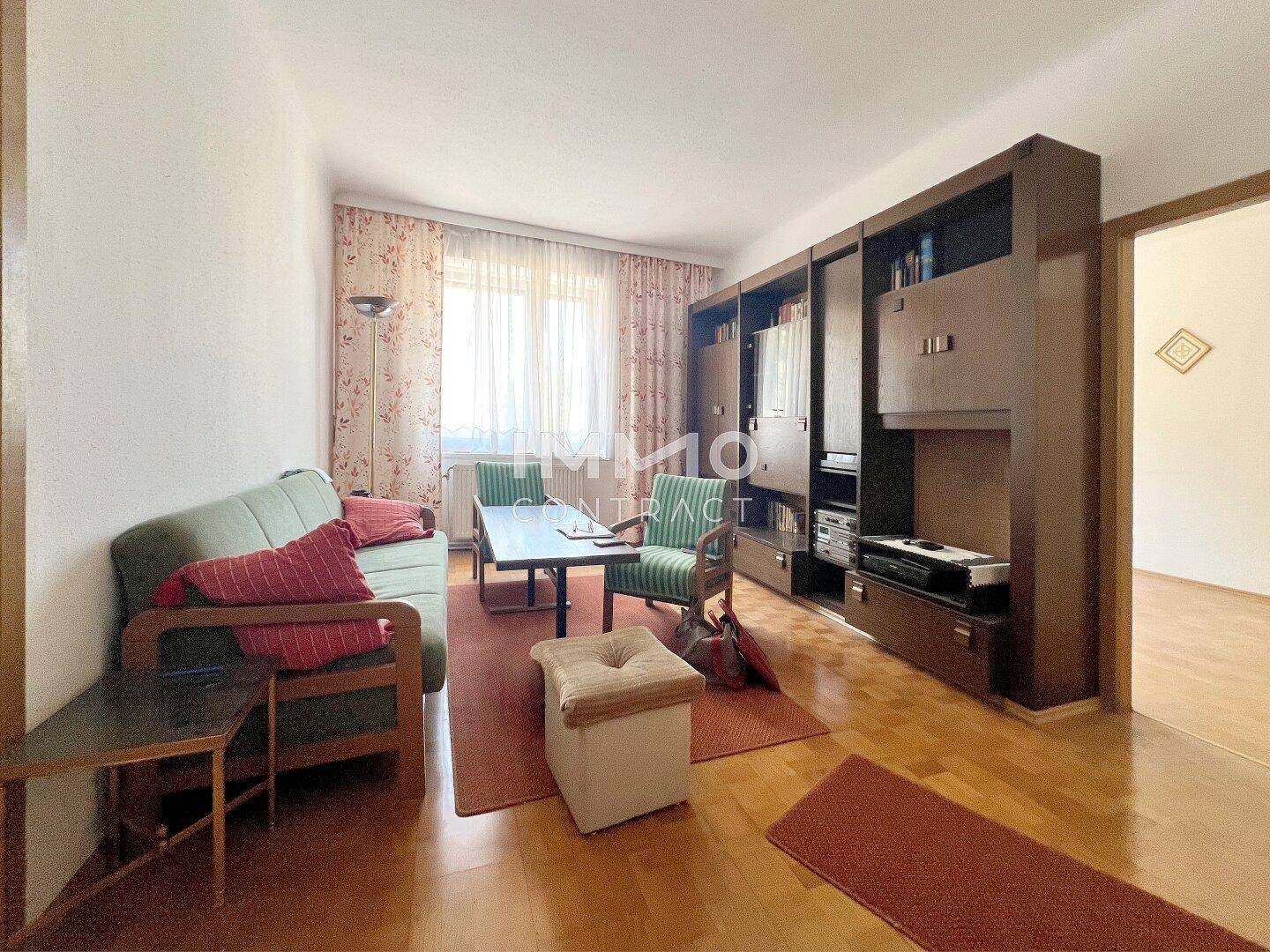 Wohnzimmer mit klassischer Einrichtung, großer Schrankwand und Parkettboden.