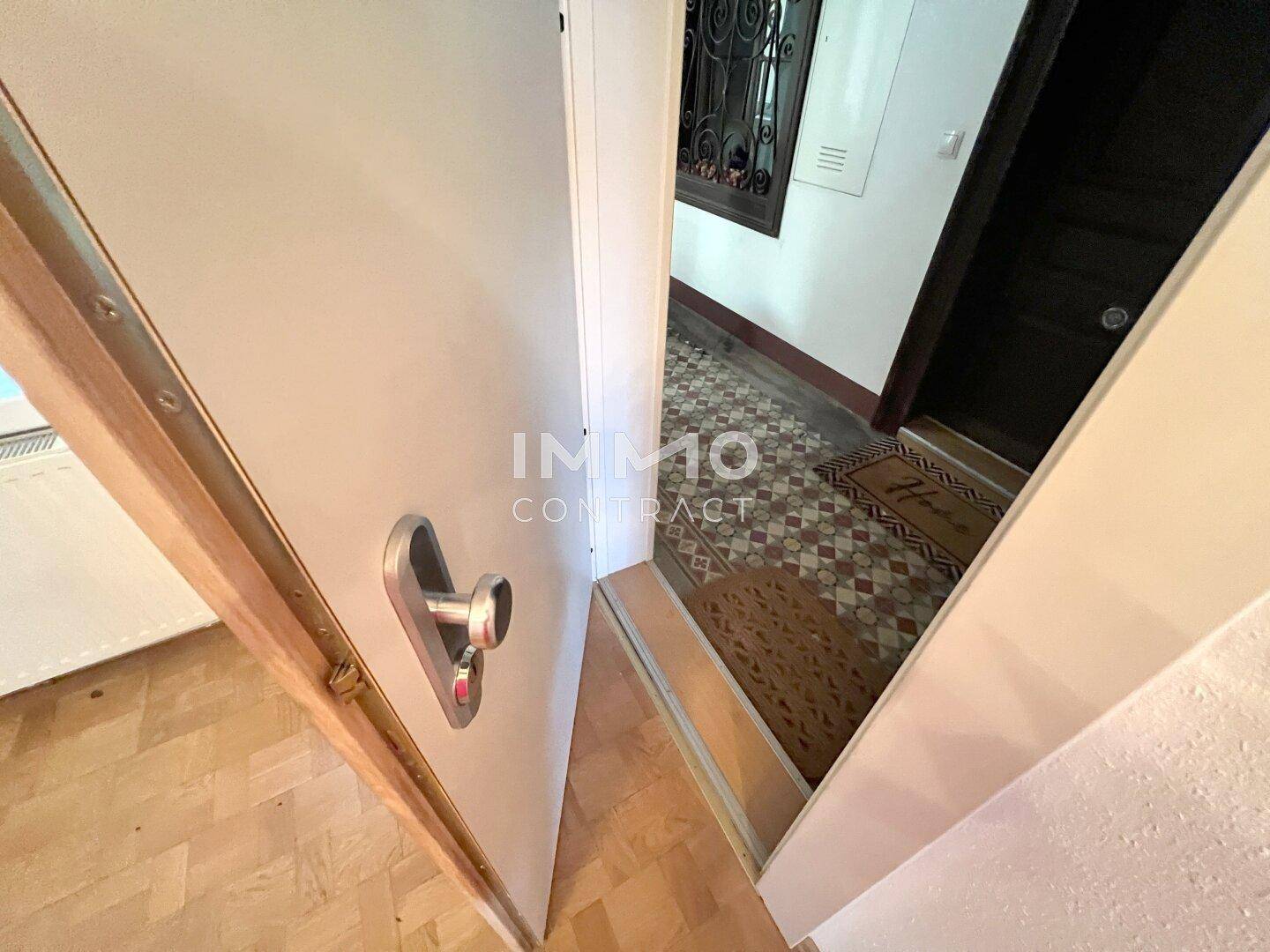 Blick aus der Wohnungstür in den gemeinschaftlichen Hausflur mit gemusterten Fliesen.