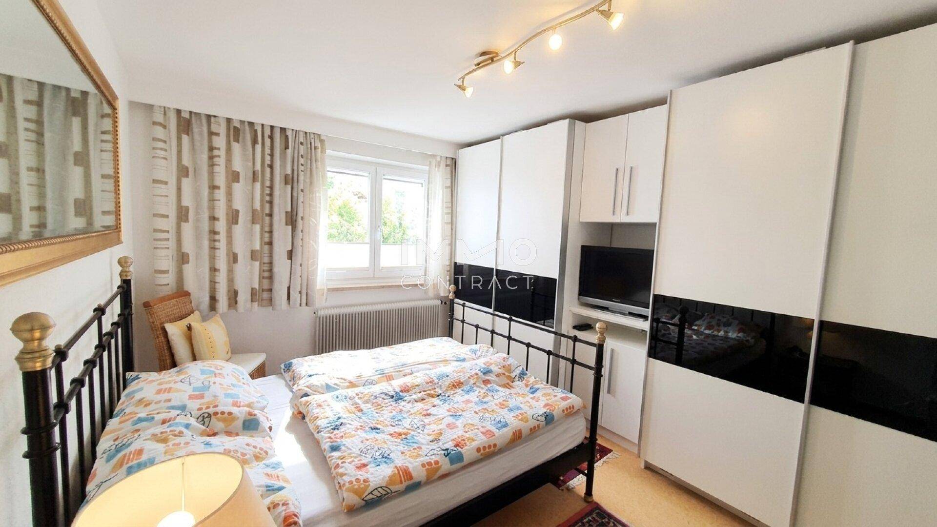 Helles Schlafzimmer mit Doppelbett, modernen Einbauschränken und Fensterblick.