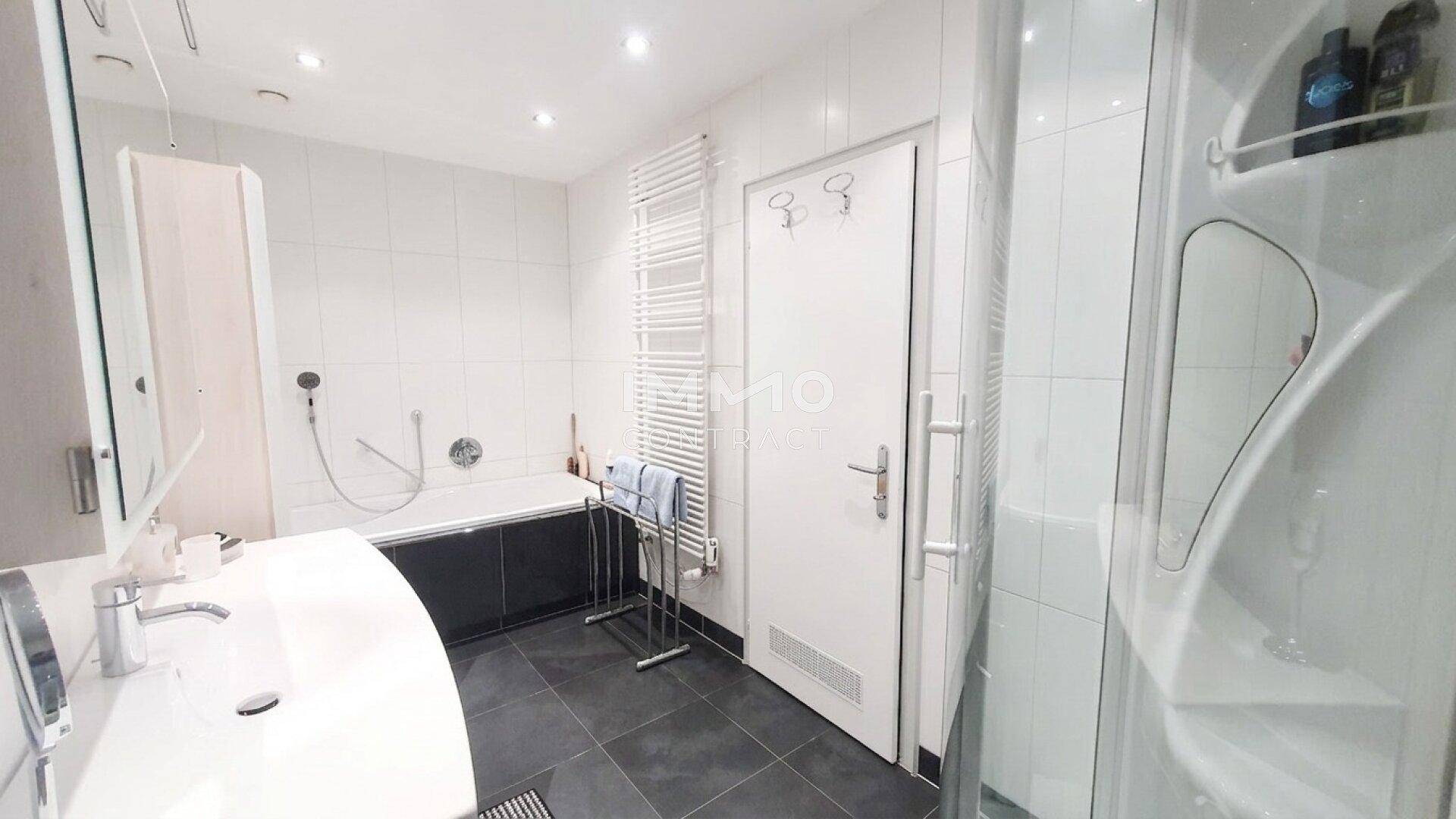 Funktionales Badezimmer mit Badewanne, Duschkabine und beheiztem Handtuchhalter.
