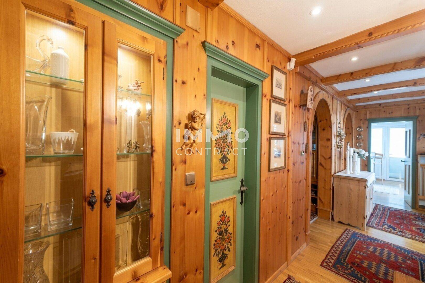 Gemütlicher Flur mit Holzwänden, Vitrinenschrank und handbemalten Türen im Landhausstil.