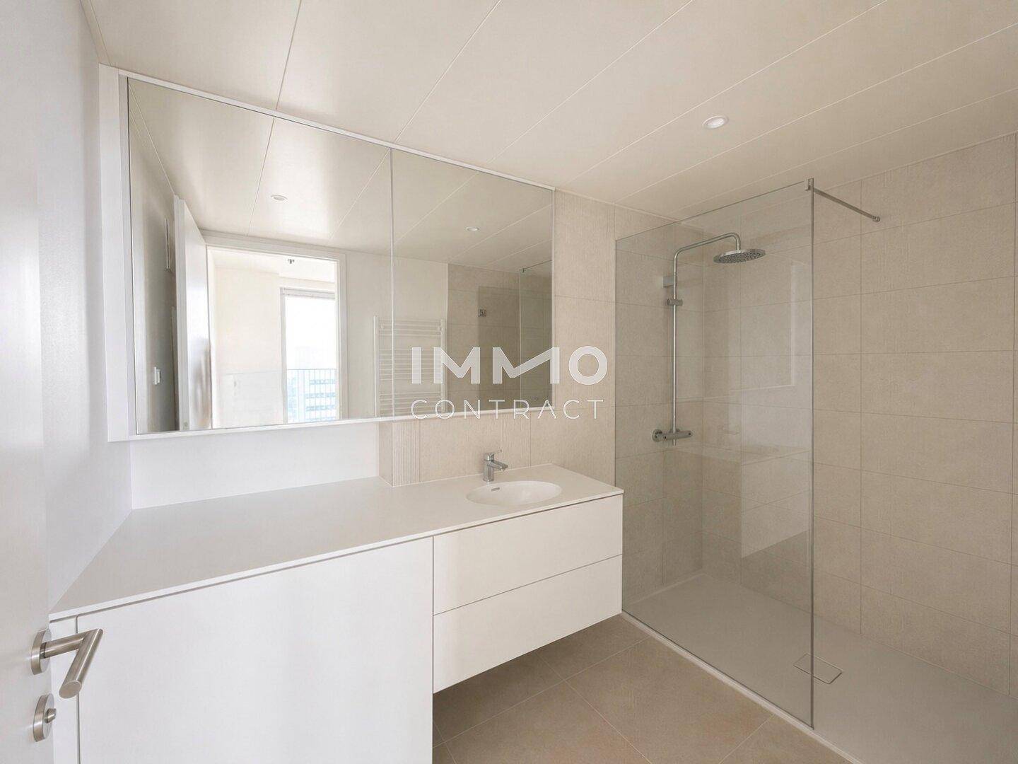 Modernes Badezimmer mit begehbarer Dusche, großem Spiegel und eleganten Fliesen.