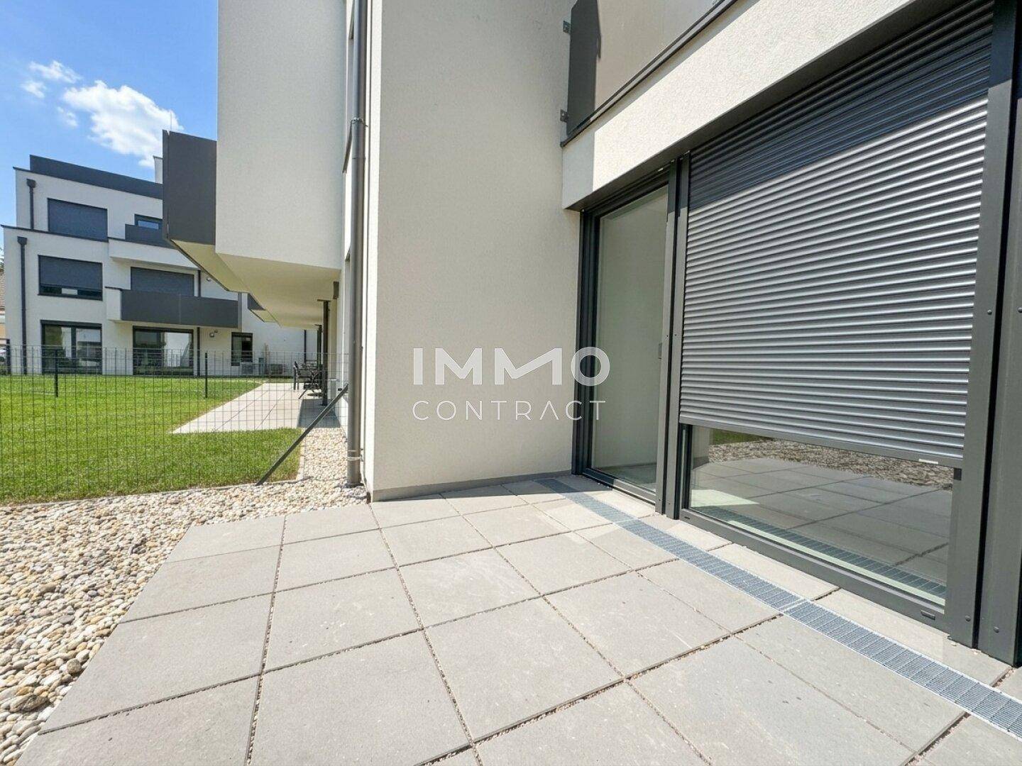 Gepflasterte Terrasse mit Kiesrand und Zugang zu einem Rasenbereich, ideal für Entspannung im Freien.