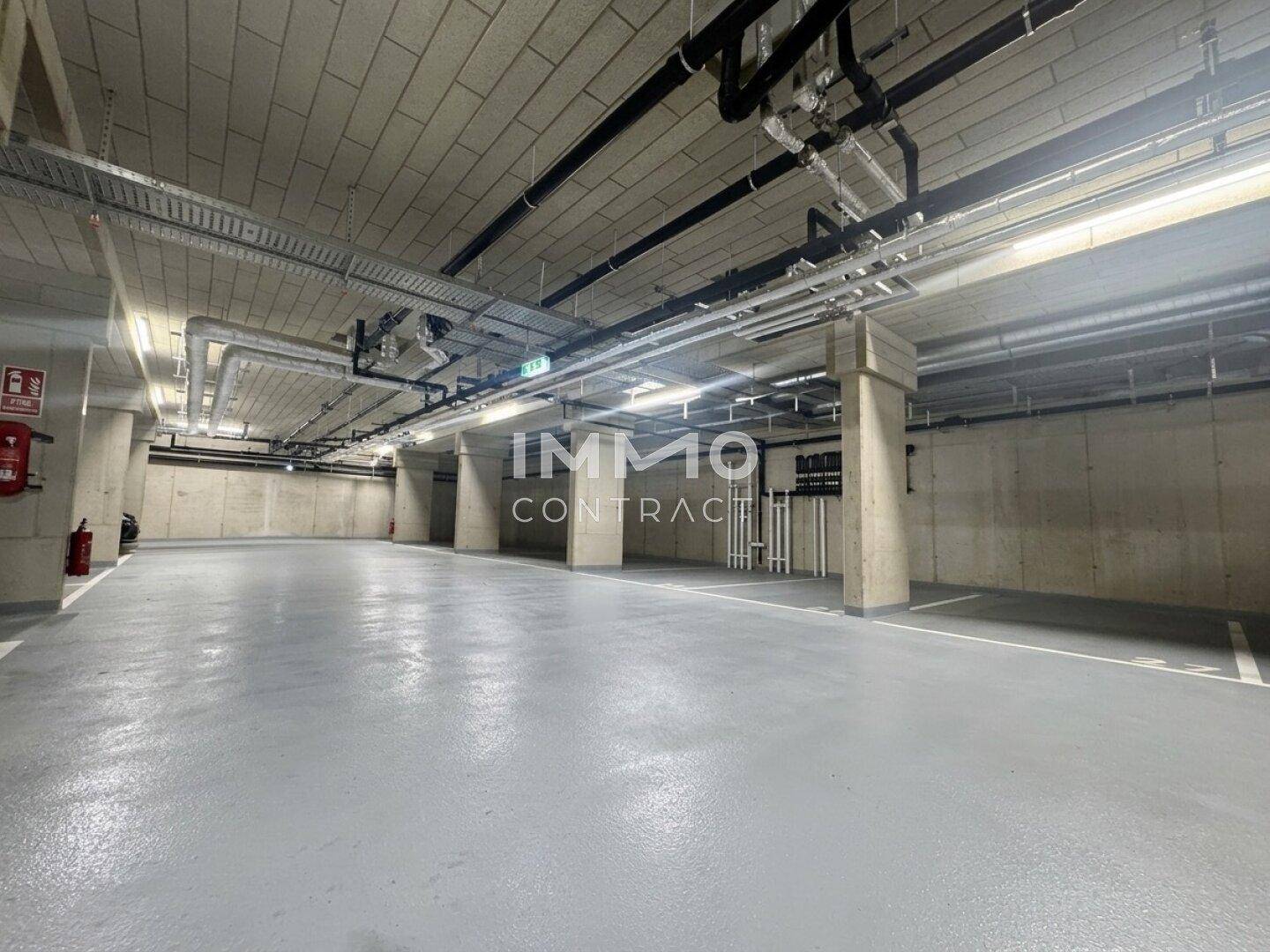 Geräumige Tiefgarage mit Betonwänden und sichtbaren Installationen.