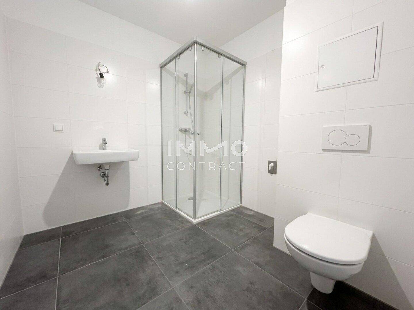 Modernes Badezimmer mit Duschkabine, Waschbecken und wandhängendem WC, ausgestattet mit weißen Fliesen.