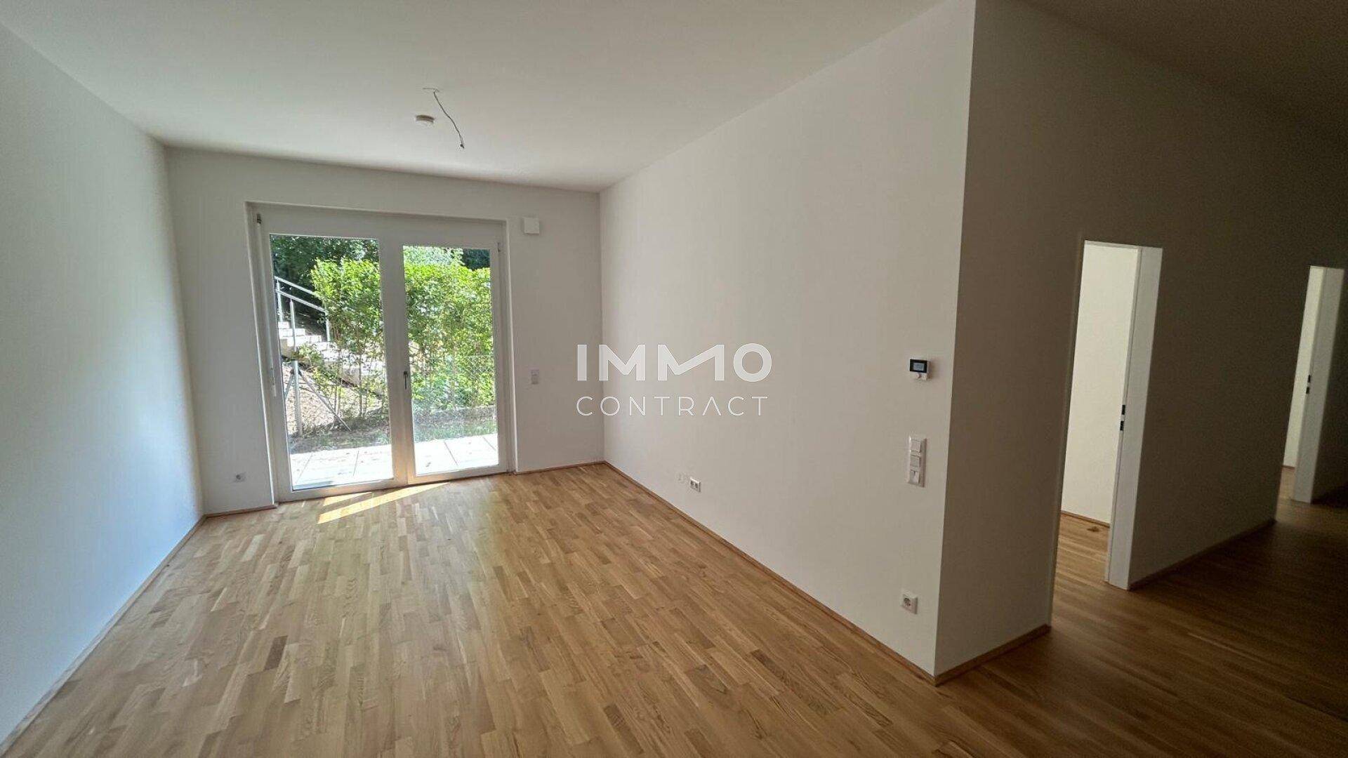 Heller Wohnraum mit Holzboden und großer Glastür zum Außenbereich.