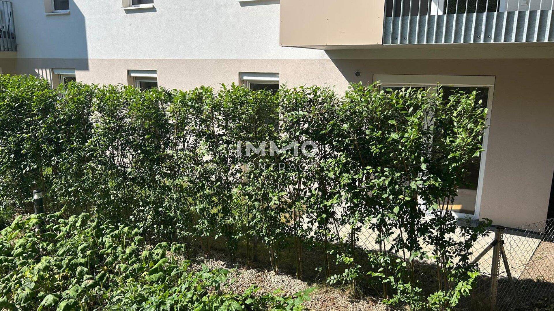 Grüner Gartenbereich mit dichter Hecke und Zugang zum Gebäude.