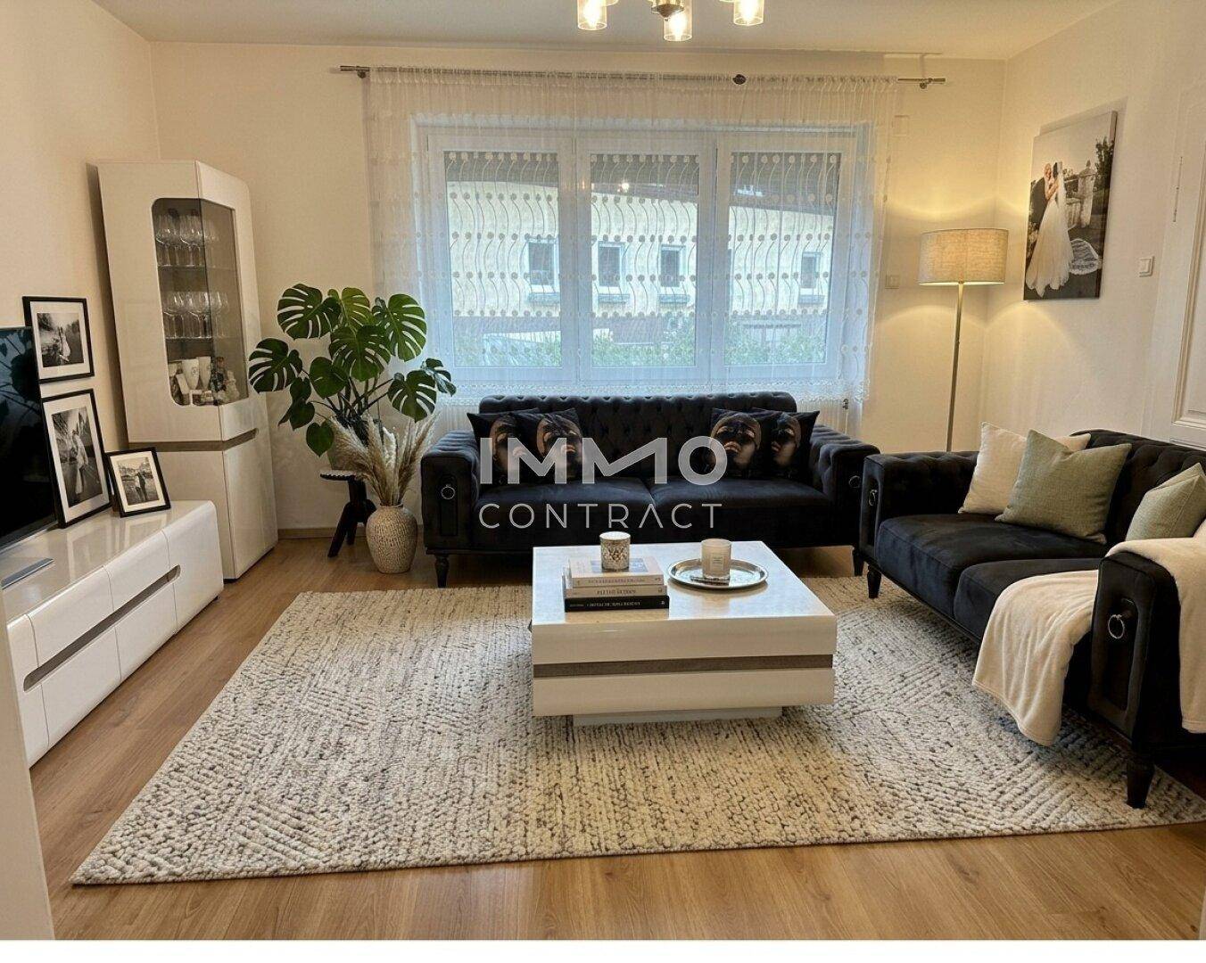 Gemütliches Wohnzimmer mit zwei dunklen Sofas, weißem Couchtisch und großem Fenster für viel Licht.