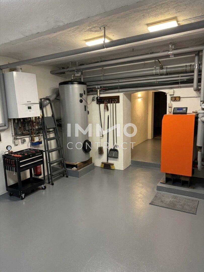 Heizungsraum im Keller mit Warmwasserspeicher, Heizkesseln und sichtbaren Rohrleitungen.