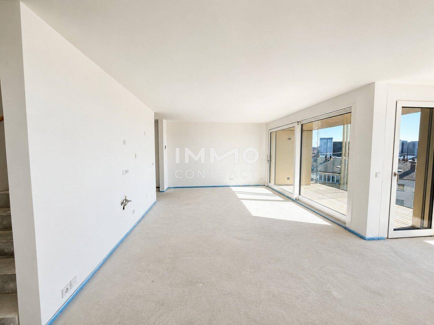Großes, helles Zimmer im Rohbau mit weitem Blick und Zugang zu einem Außenbereich.