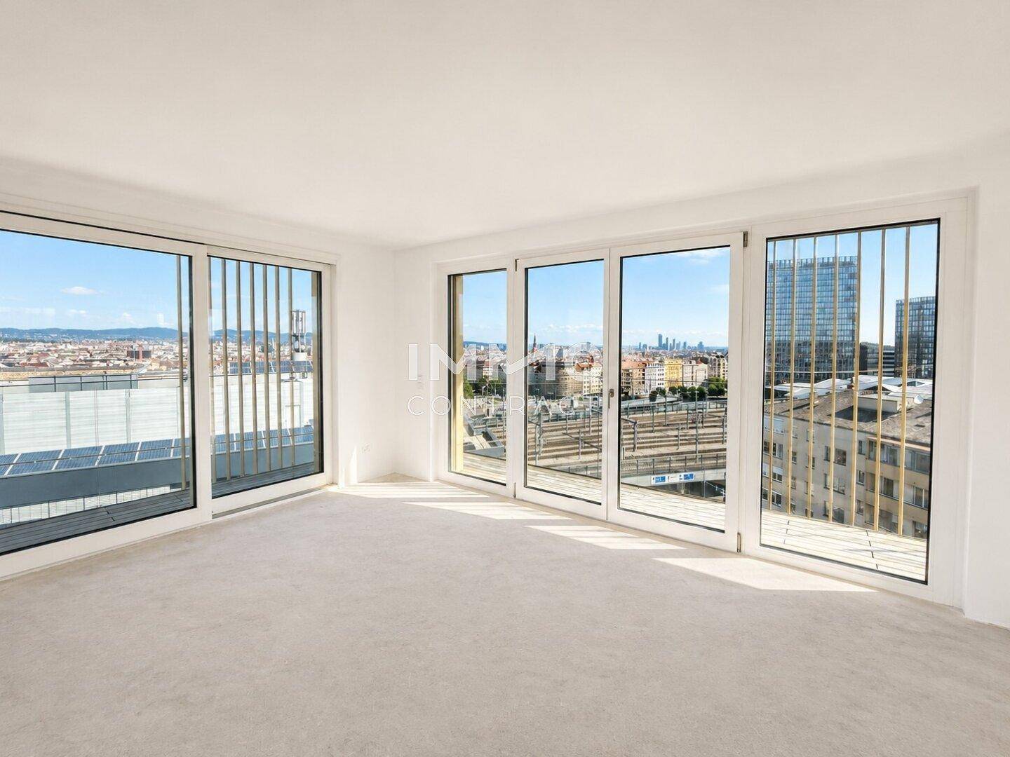 Heller Wohnraum mit mehreren großen Fenstern, die einen umfassenden Stadtblick bieten.