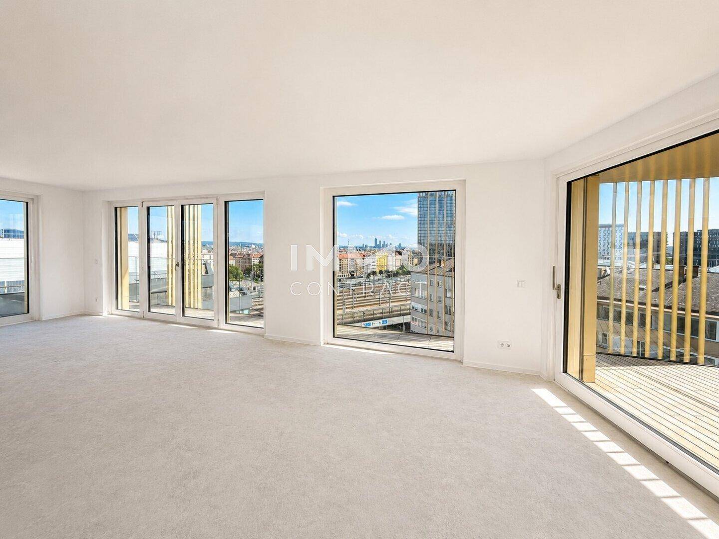 Heller Wohnraum mit Teppichboden, großen Fenstern und Zugang zum Balkon mit Stadtblick.