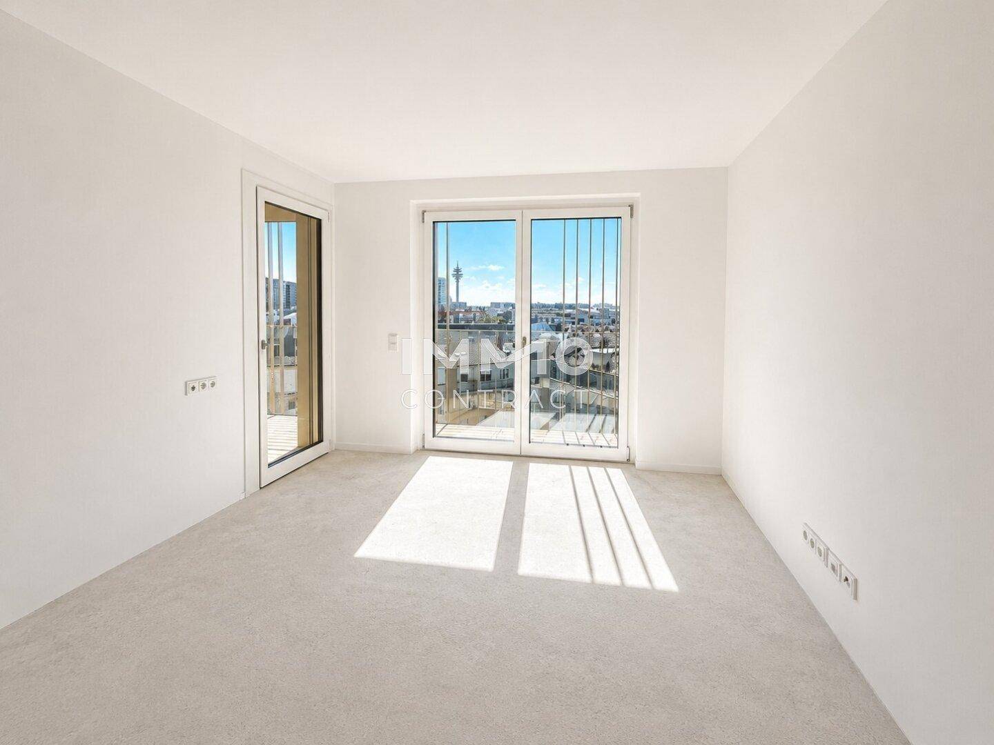 Helles Schlafzimmer mit Teppichboden und großem Fenster mit Blick auf die Stadt.