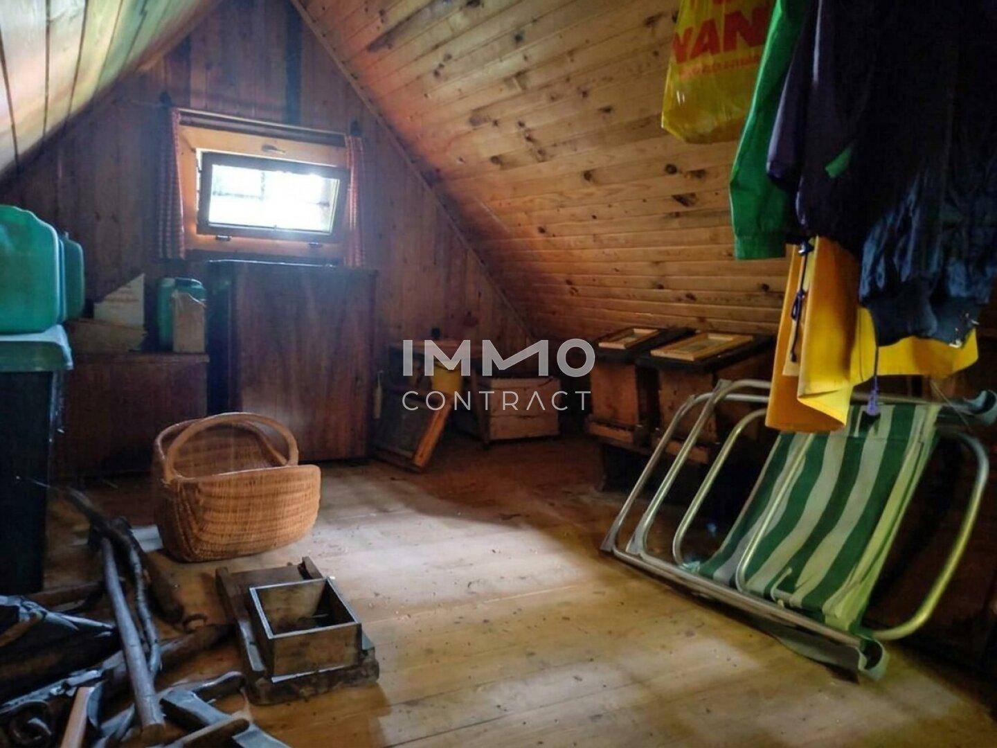Dachboden der Holzhütte mit Holzvertäfelung, Dachfenster und Stauraum.