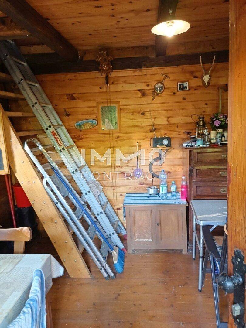 Innenraum der Holzhütte mit Leiter zum Dachboden und rustikaler Einrichtung.