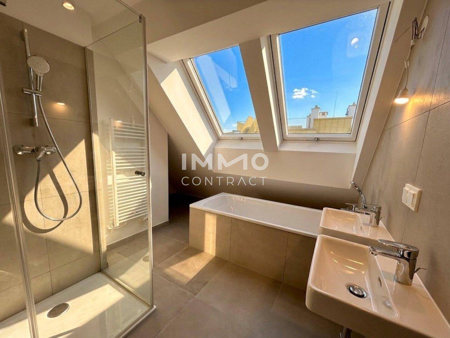 Modernes Badezimmer im Dachgeschoss mit Dusche, Badewanne und doppelten Dachfenstern für viel Helligkeit.