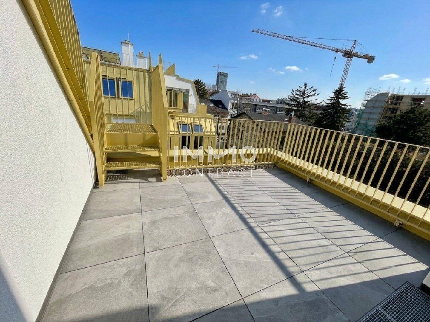 Geräumige Dachterrasse mit Fliesenboden und gelbem Geländer, bietet Platz für Outdoor-Möbel und Blick auf die Stadt.
