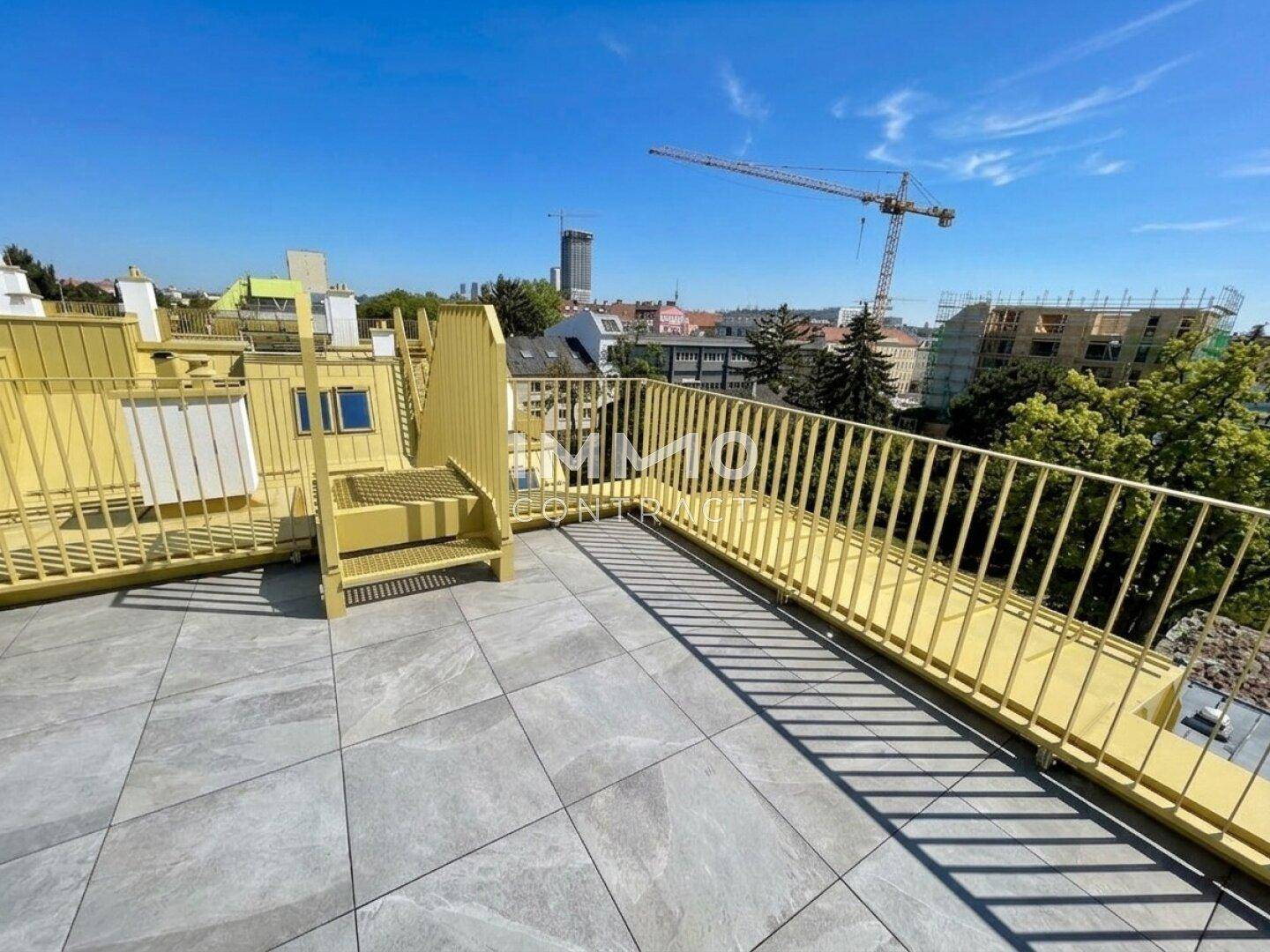 Weitläufige Dachterrasse mit gelbem Geländer und urbanem Ausblick, perfekt für sonnige Tage.
