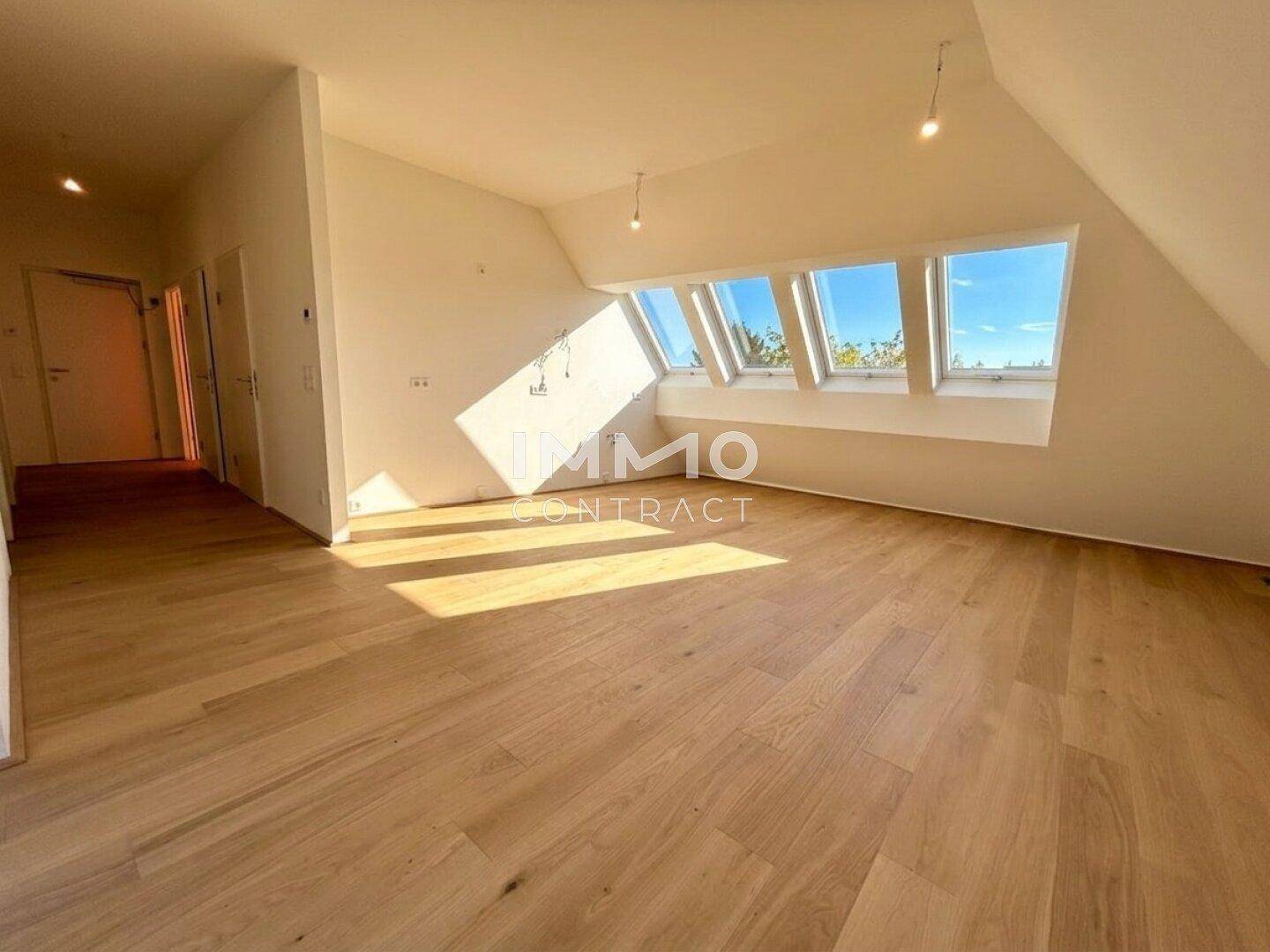 Lichtdurchfluteter Dachgeschossraum mit neuem Holzboden und schrägen Wänden.