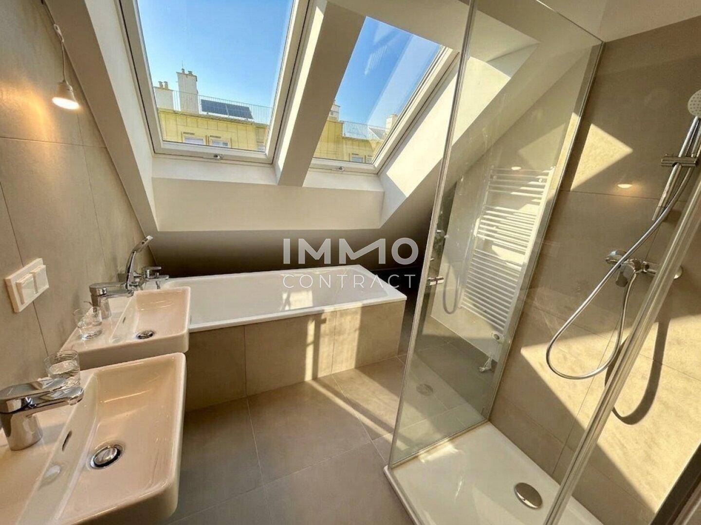 Modernes Badezimmer im Dachgeschoss mit Doppelwaschbecken, Badewanne, Dusche und Dachfenstern.