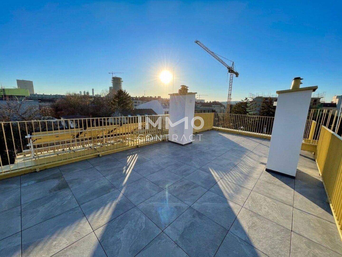 Dachterrasse mit Fliesenboden und gelbem Geländer, bietet einen malerischen Blick bei Sonnenuntergang.