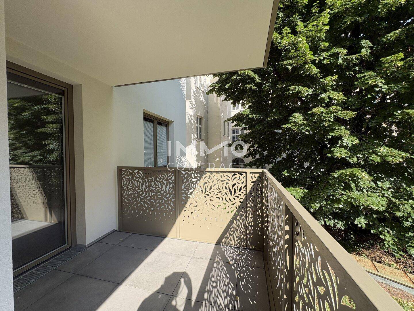 Balkon mit modernem, dekorativem Geländer und Blick auf Bäume und umliegende Gebäude.