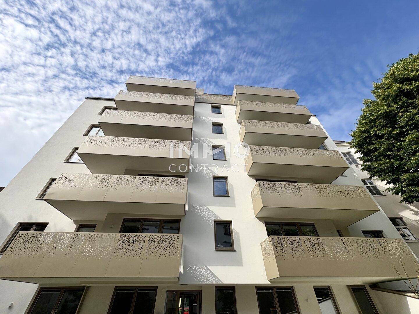 Moderne Gebäudefassade mit gestuften Balkonen, von unten gegen den blauen Himmel fotografiert.