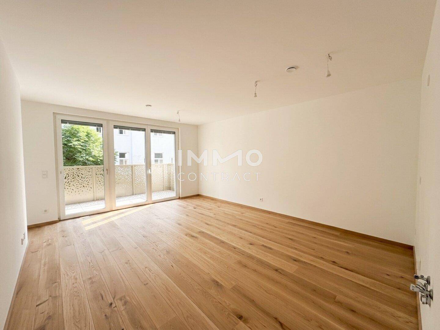Leerer Raum mit hellem Holzboden und großer Balkontür, bereit zur individuellen Gestaltung.