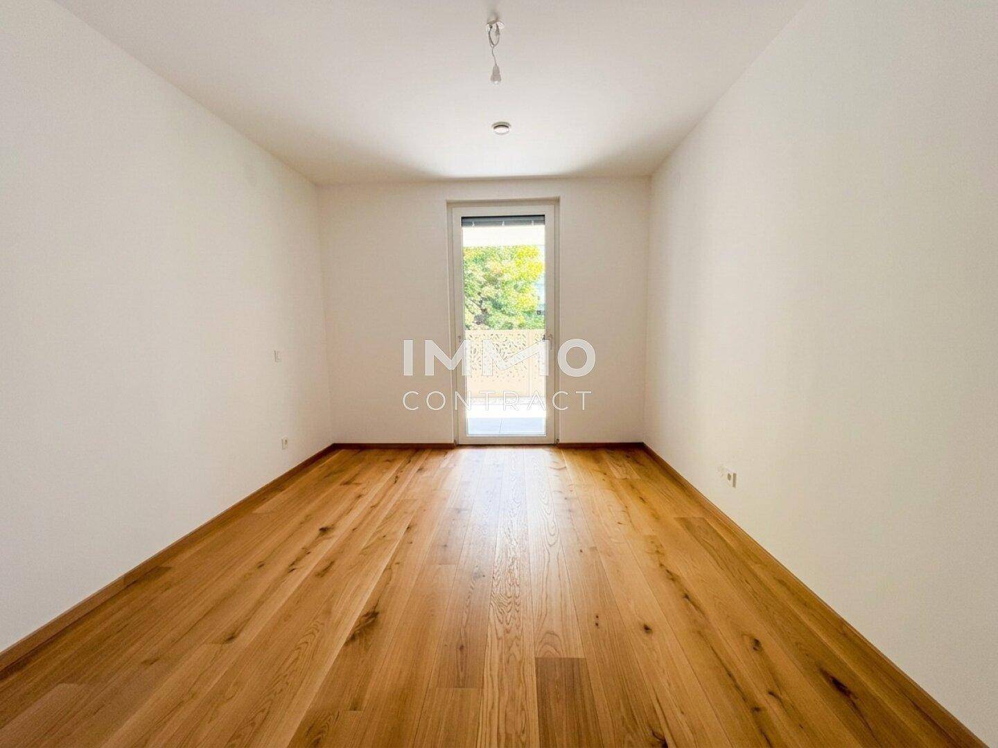 Leeres Schlafzimmer mit hellem Holzboden und Zugang zu einem Außenbereich, bereit zur Einrichtung.