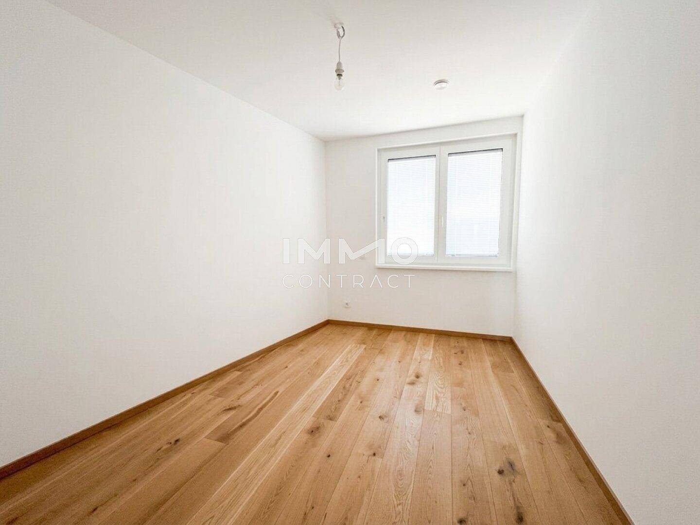 Leeres Schlafzimmer mit hellem Holzboden und Fenster, bietet viel Potenzial für individuelle Gestaltung.