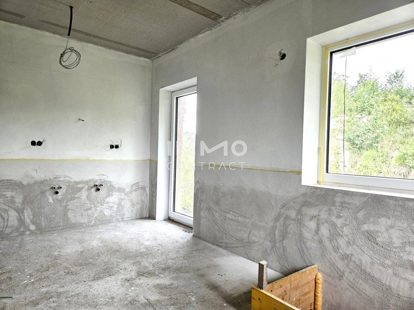 Rohbau eines Raumes mit Fenster, Tür und vorbereiteten Wandbereichen.