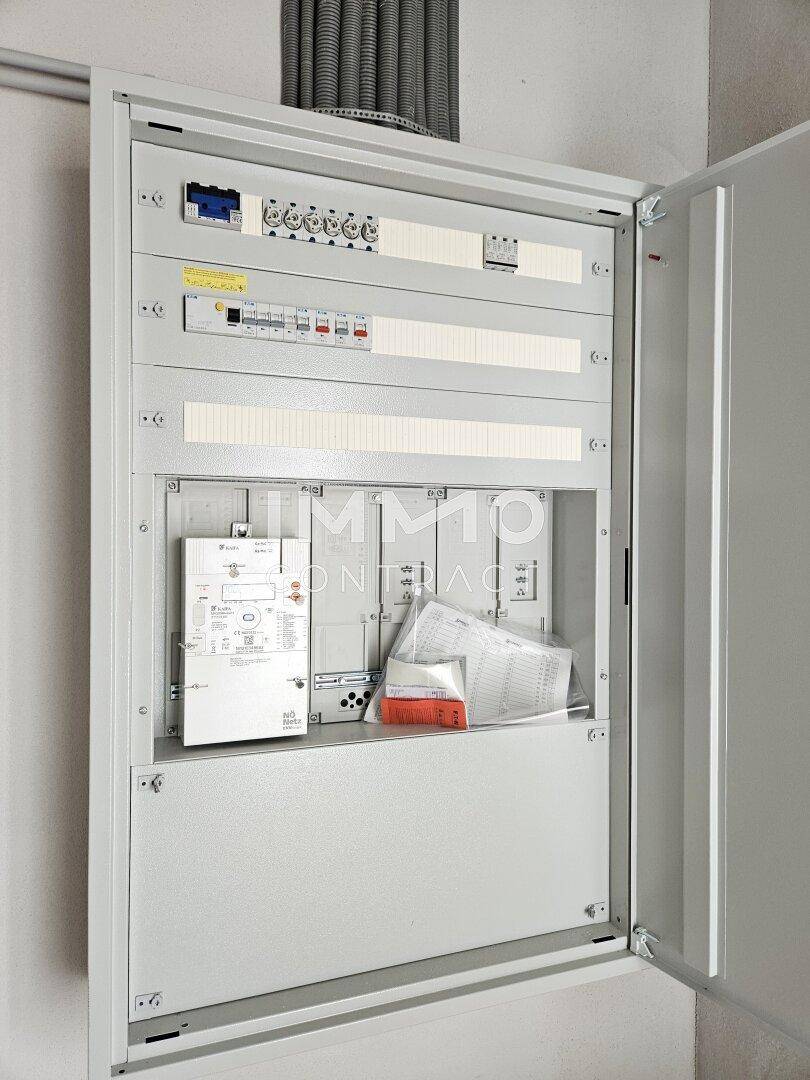 Offener Elektroverteilerkasten mit Sicherungen und Verkabelung, zeigt die moderne Elektroinstallation des Hauses.