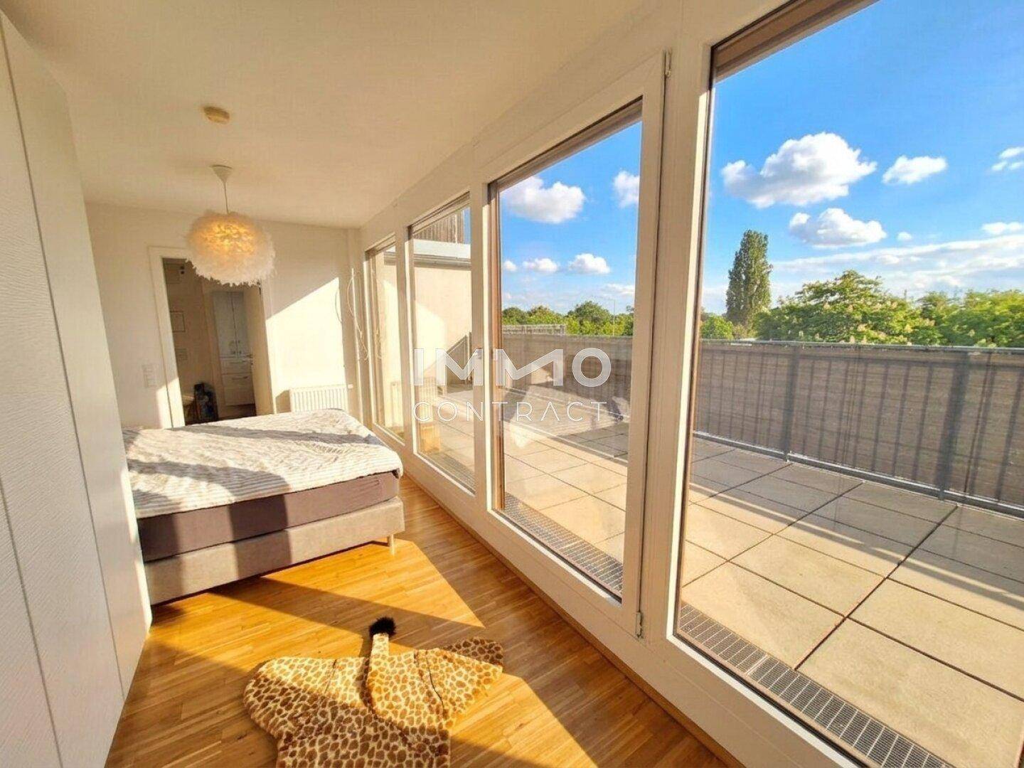Schlafzimmer mit viel Tageslicht, Holzboden und direktem Zugang zur Außenterrasse.