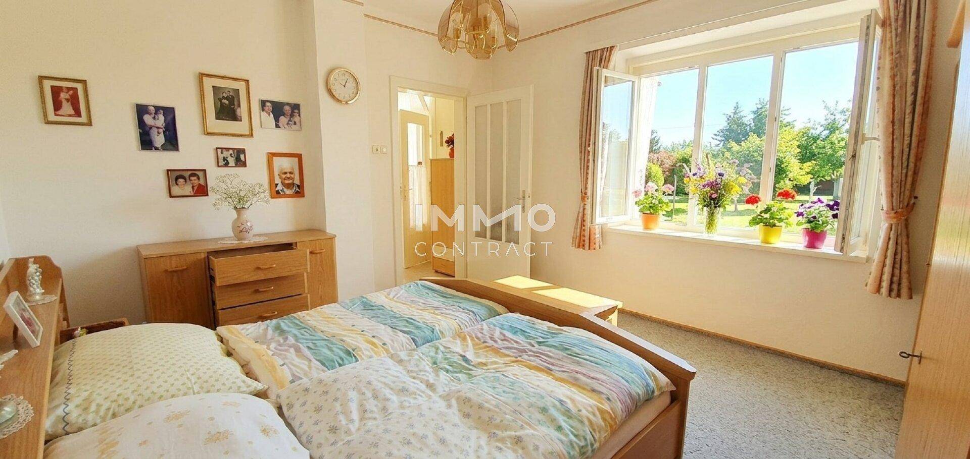 Gemütliches Schlafzimmer mit Doppelbett und großem Fenster mit Blick ins Grüne.