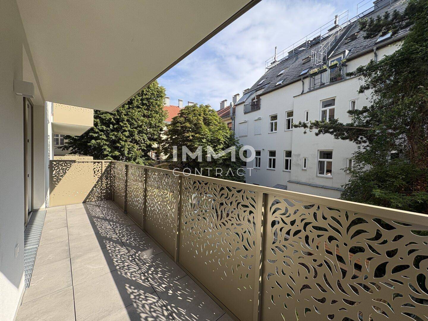 Heller Balkon mit modernen, gemusterten Geländern und Blick auf die umliegenden Gebäude.