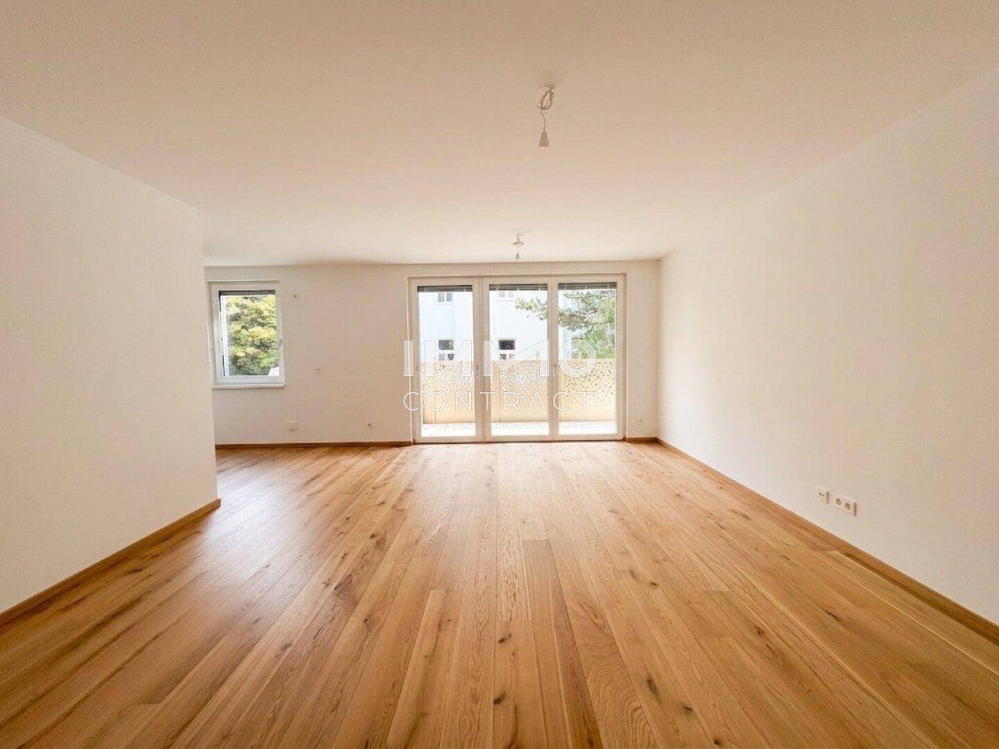 Heller, leerer Raum mit Eichenparkettboden und Zugang zu einem Balkon.