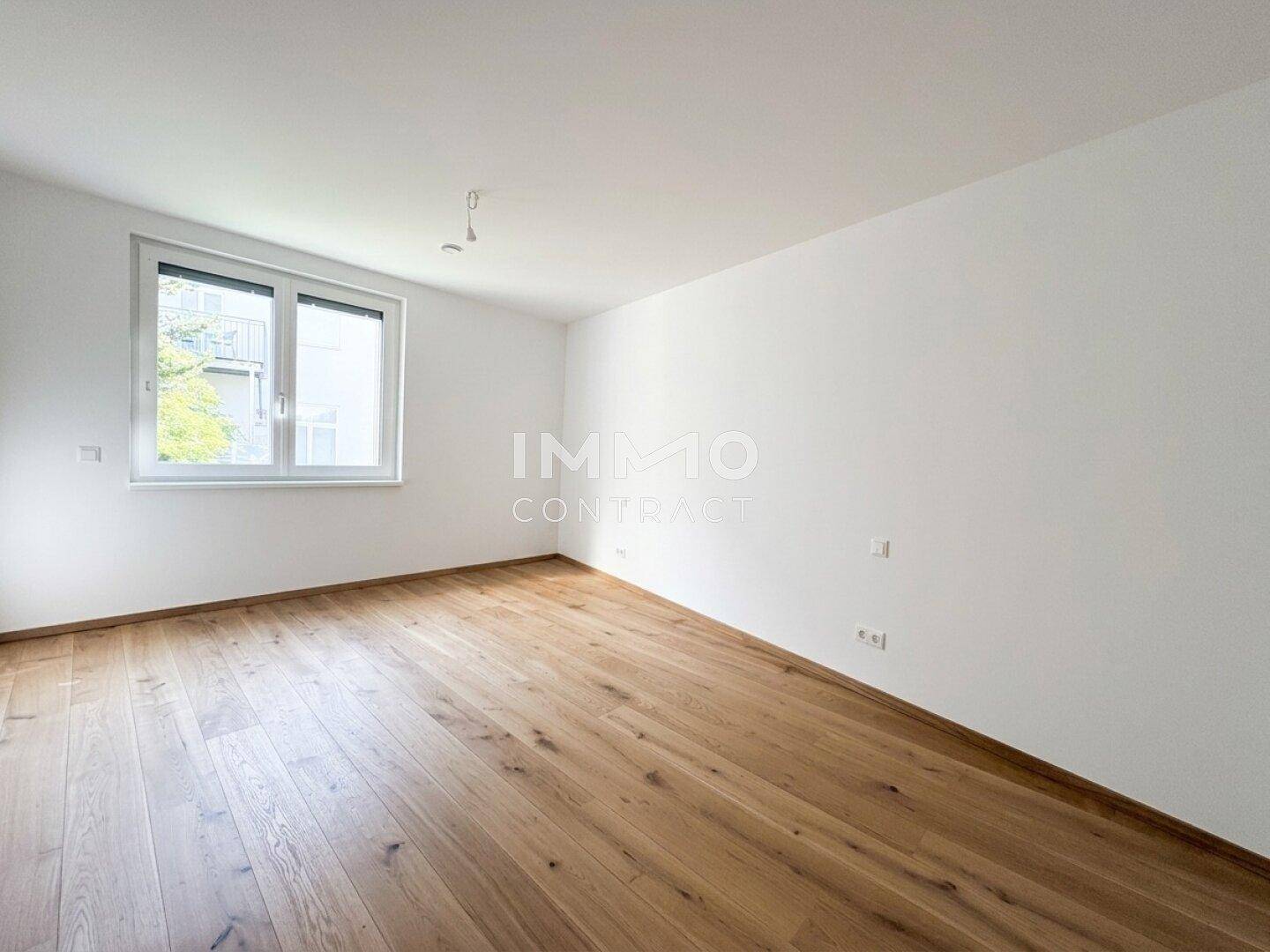 Geräumiger, heller Raum mit Eichenparkettboden und großem Fenster.