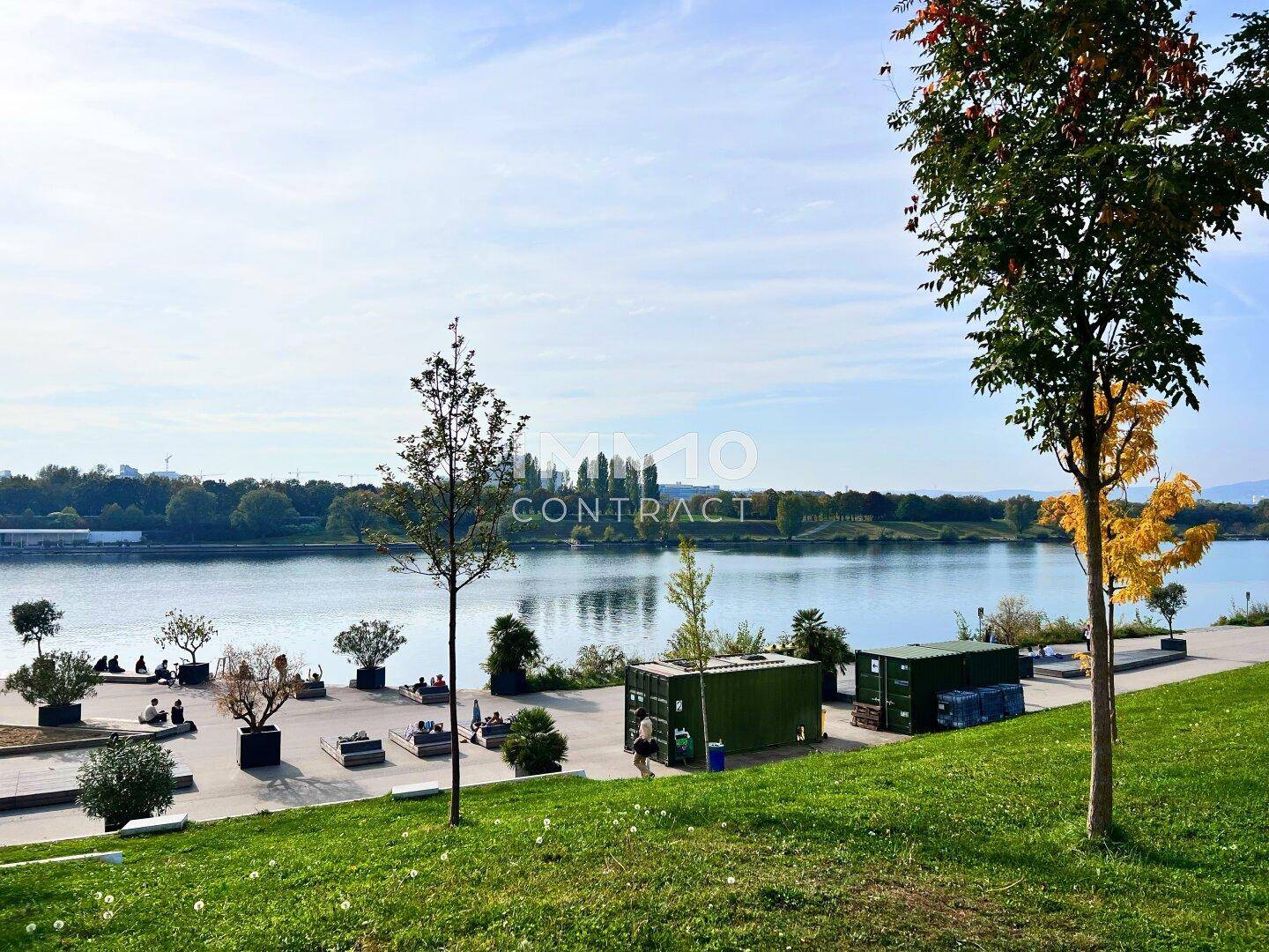 Malerischer Blick auf den See mit Grünflächen und Erholungsbereichen am Ufer.