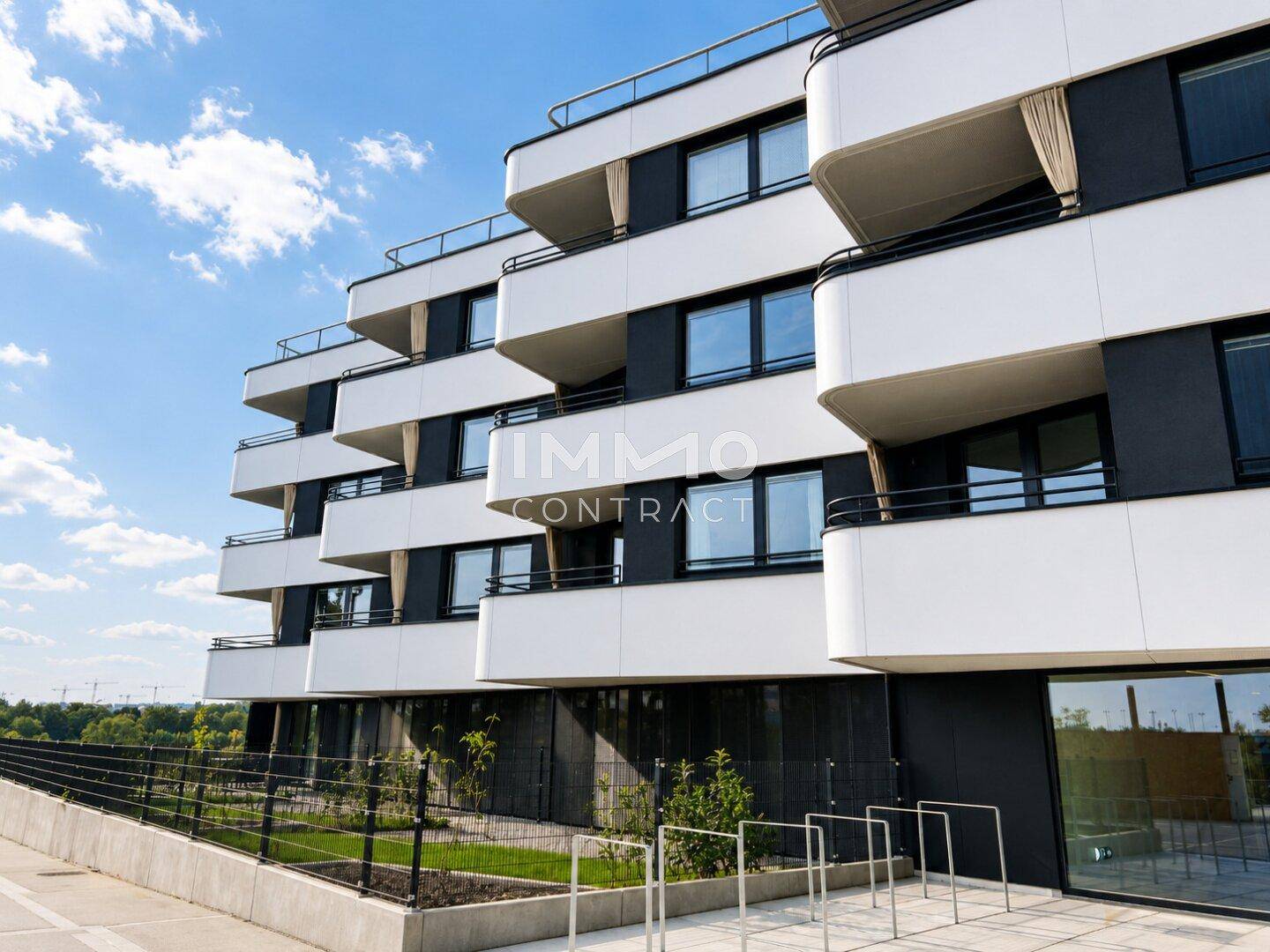 Moderne Architektur des Wohngebäudes mit gestuften Balkonen und großen Fensterfronten.