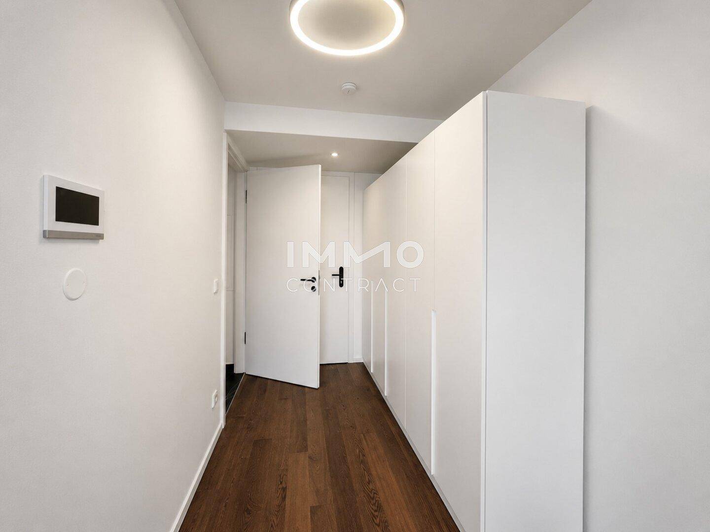 Heller Flur mit integrierten weißen Einbauschränken und dunklem Holzfußboden.