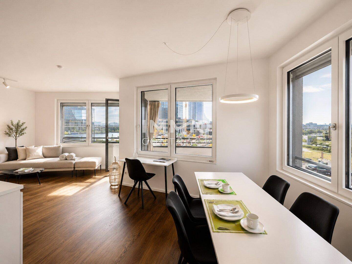 Heller Wohn- und Essbereich mit modernem Mobiliar und weitem Blick auf die Stadt.