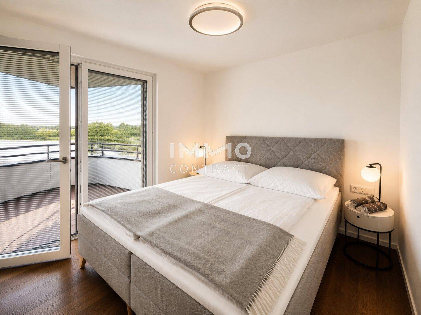 Modernes Schlafzimmer mit Doppelbett, Nachttischen und direktem Zugang zum Balkon.