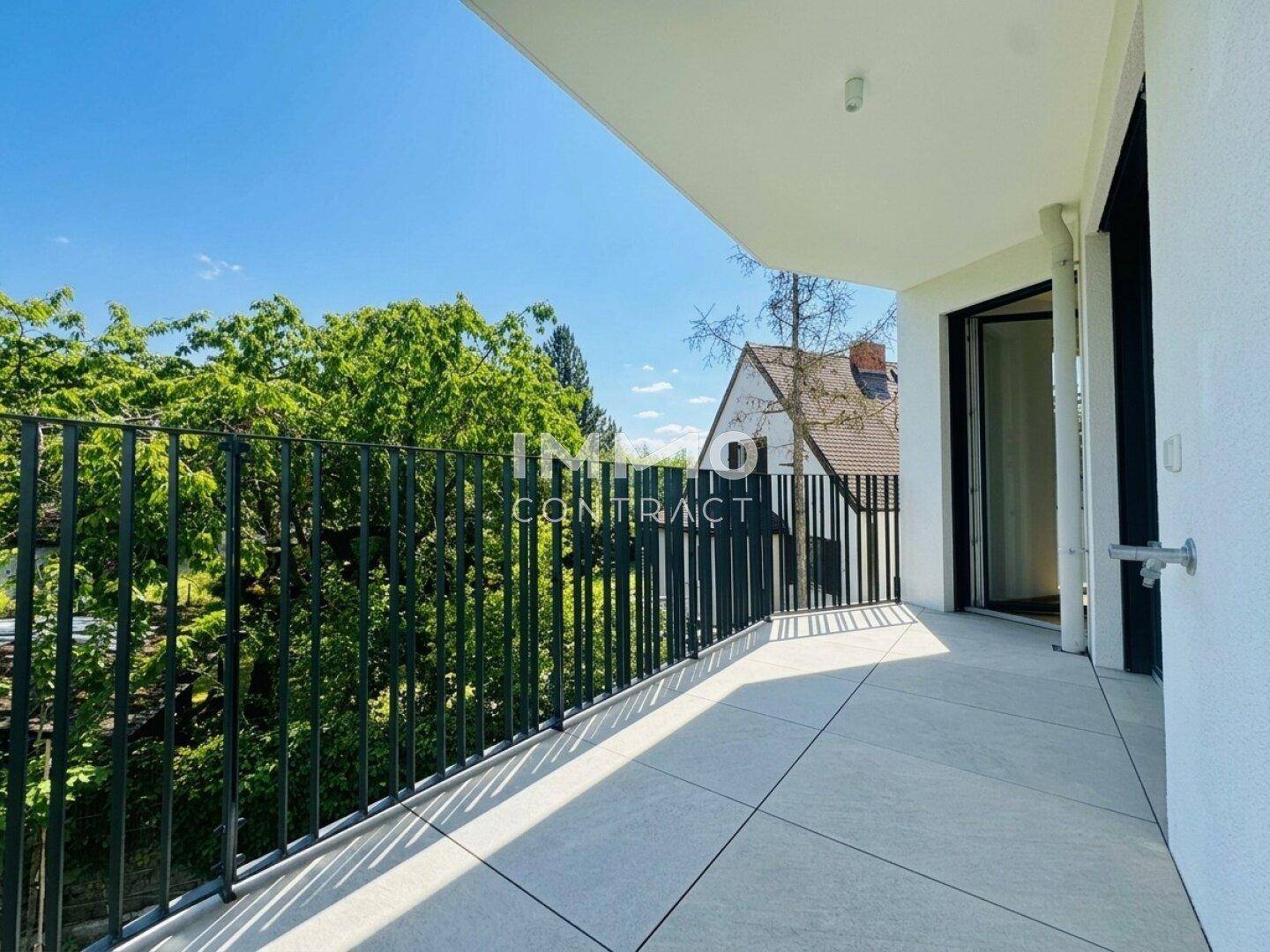 Geräumiger Balkon mit Fliesenboden und modernem Geländer, bietet einen schönen Blick ins Grüne.
