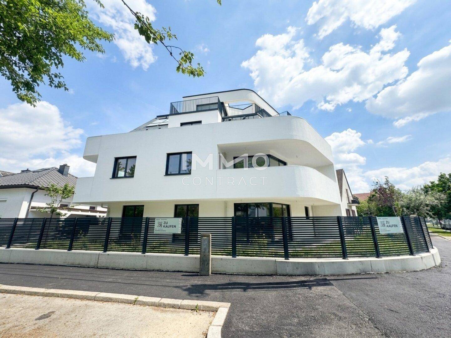 Modernes Mehrfamilienhaus mit geschwungenen Balkonen und einer eleganten Fassade.