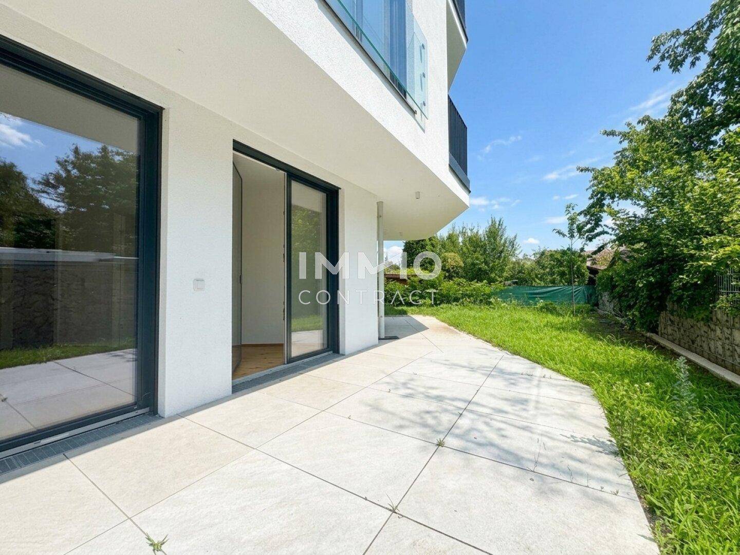 Helle, geflieste Terrasse mit großen Glasschiebetüren und Zugang zum Gartenbereich.